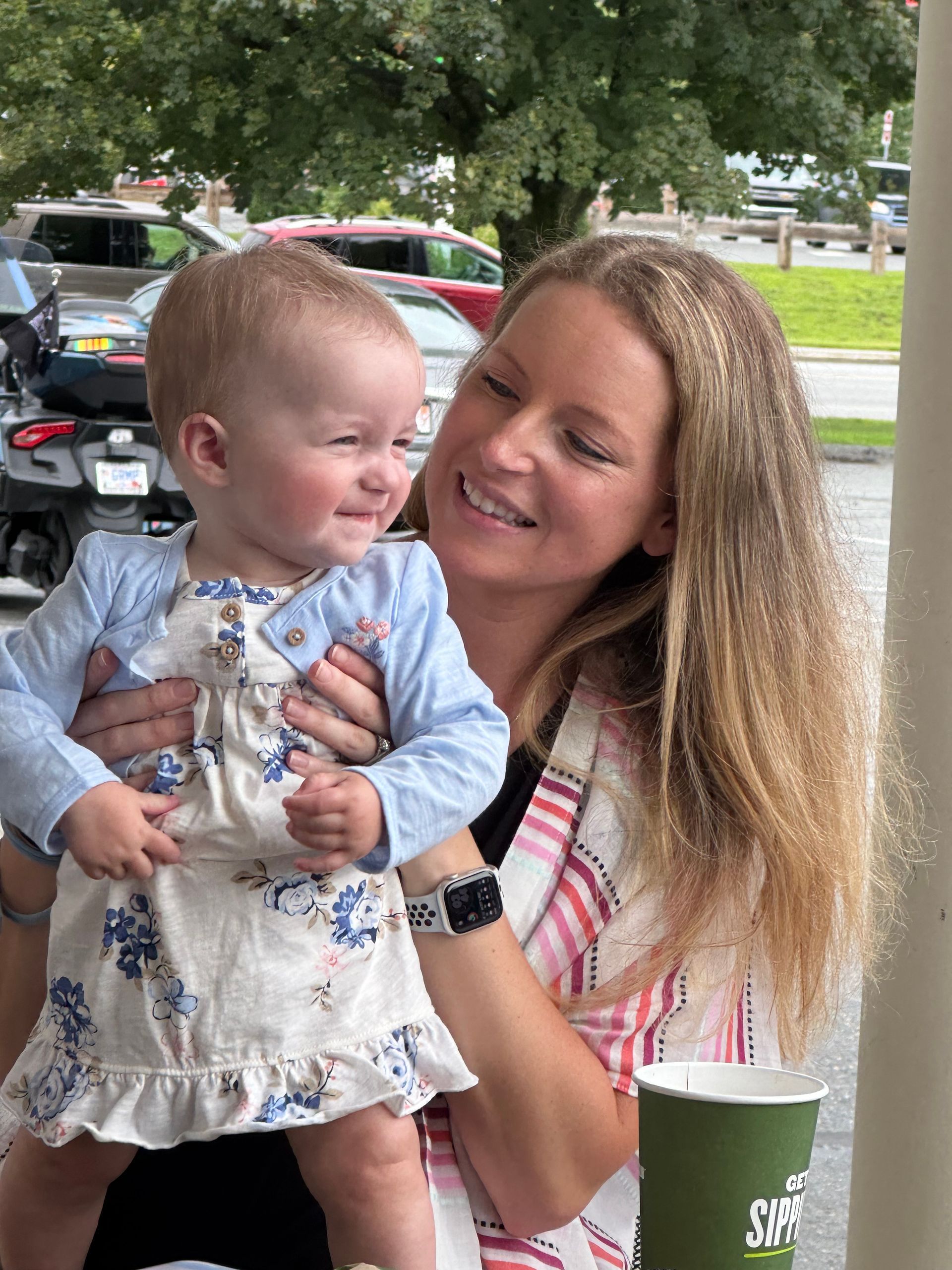 A woman is holding a baby in her arms and smiling.