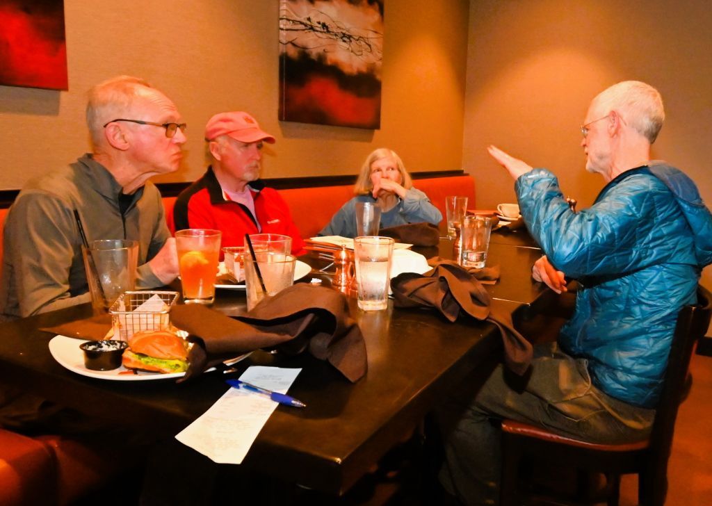 A group of people are sitting around a table in a parking lot.