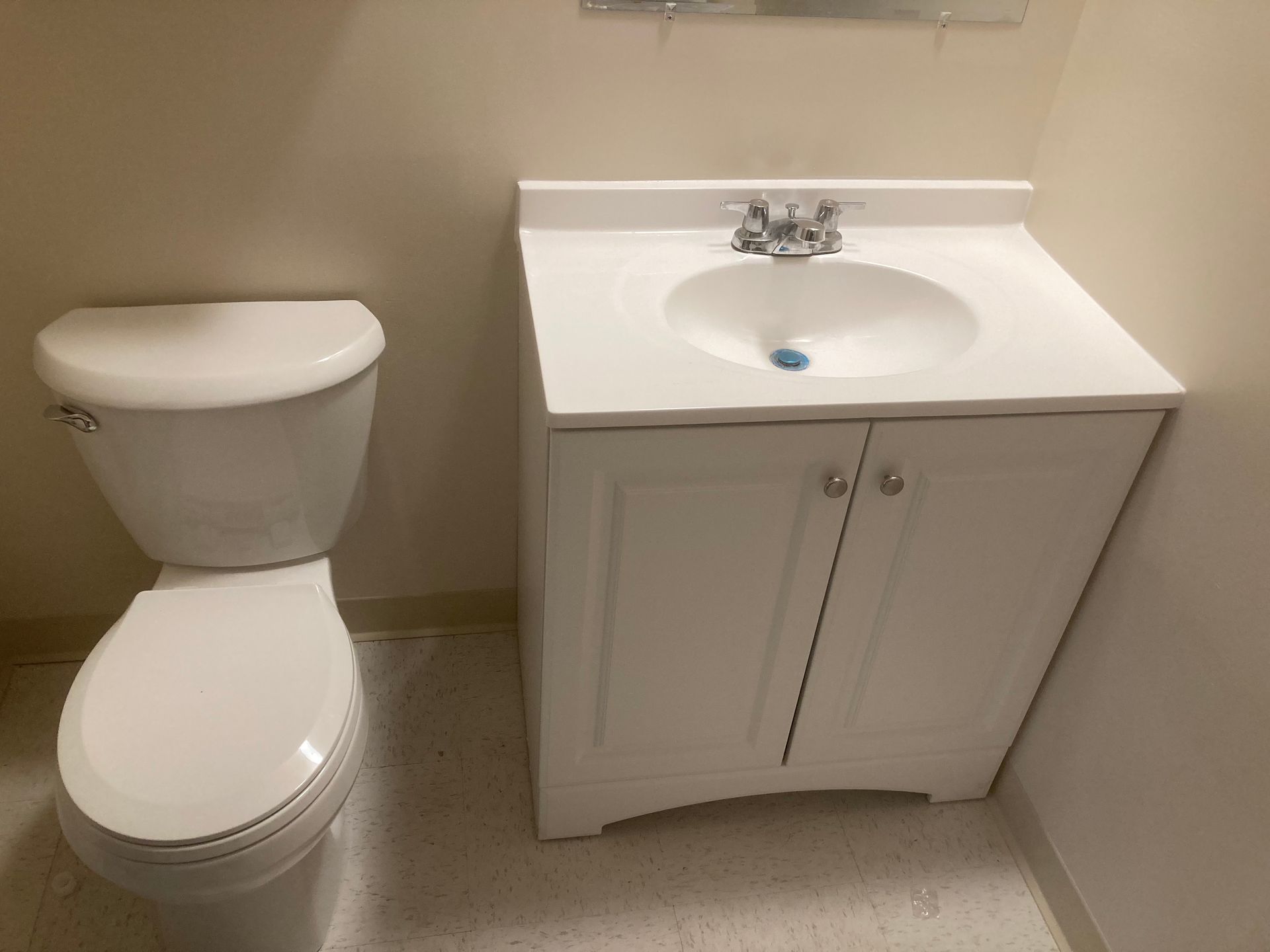A bathroom with a toilet , sink and cabinet.