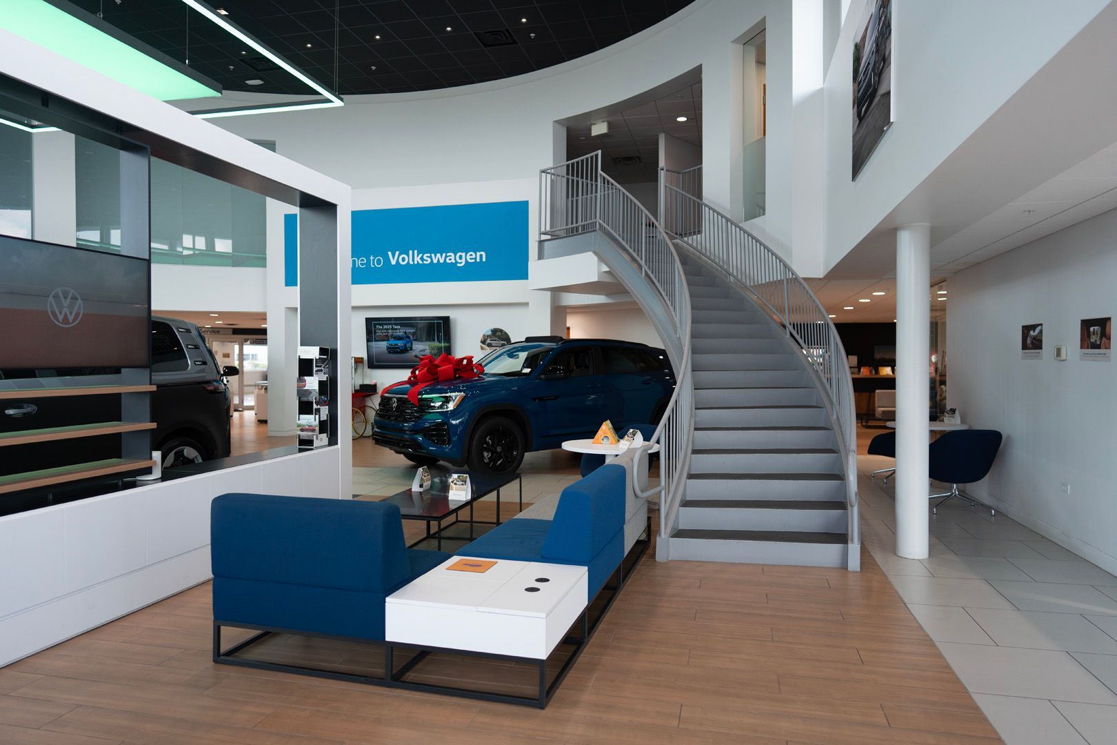 A car is on display in a car dealership with stairs leading up to it