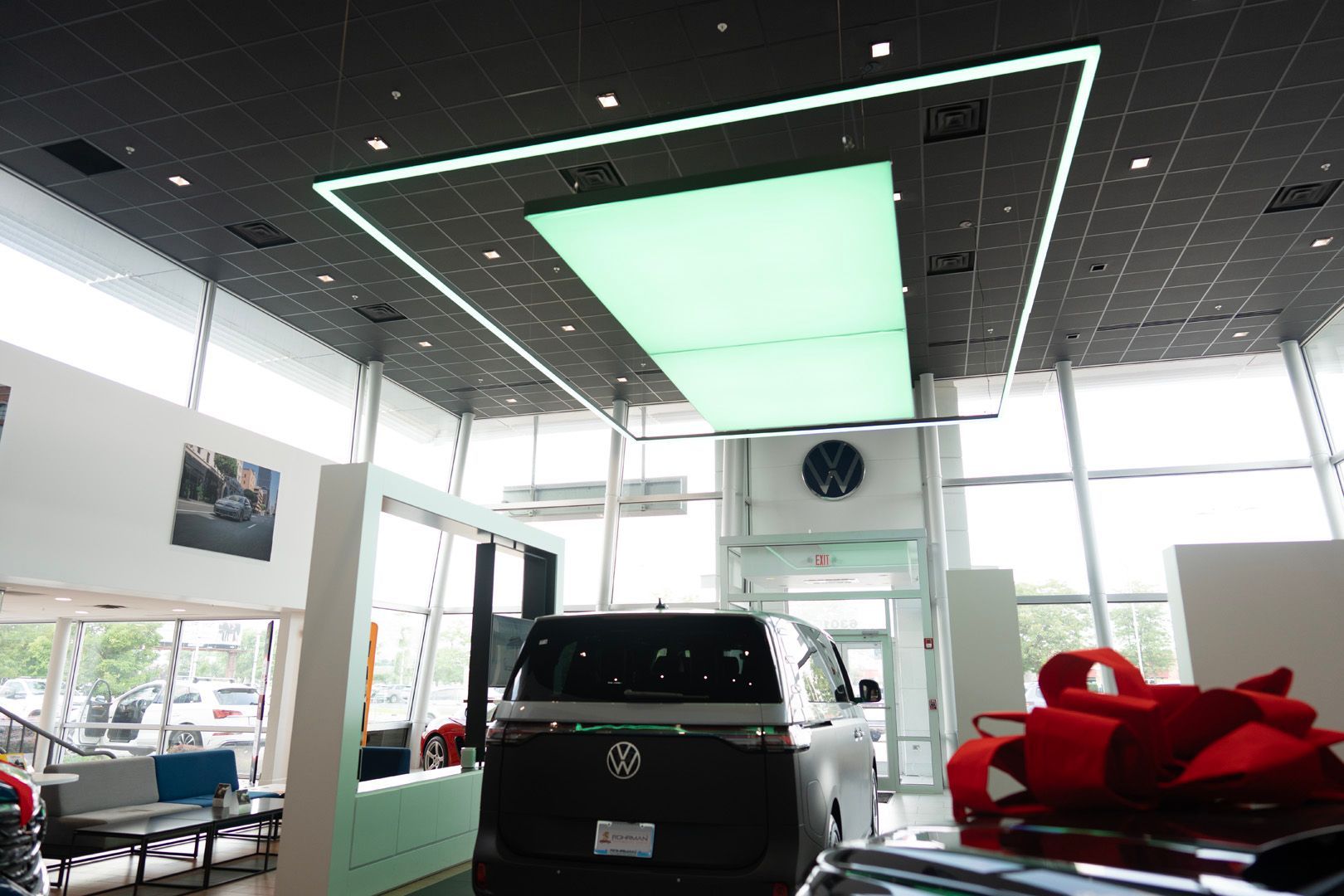 A car is parked in a showroom with a green light hanging from the ceiling.