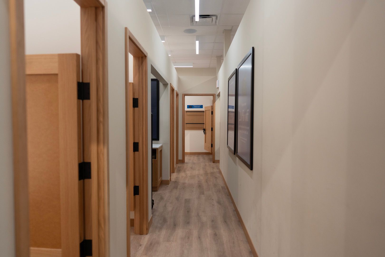 A long hallway with wooden floors and doors in a dental office.