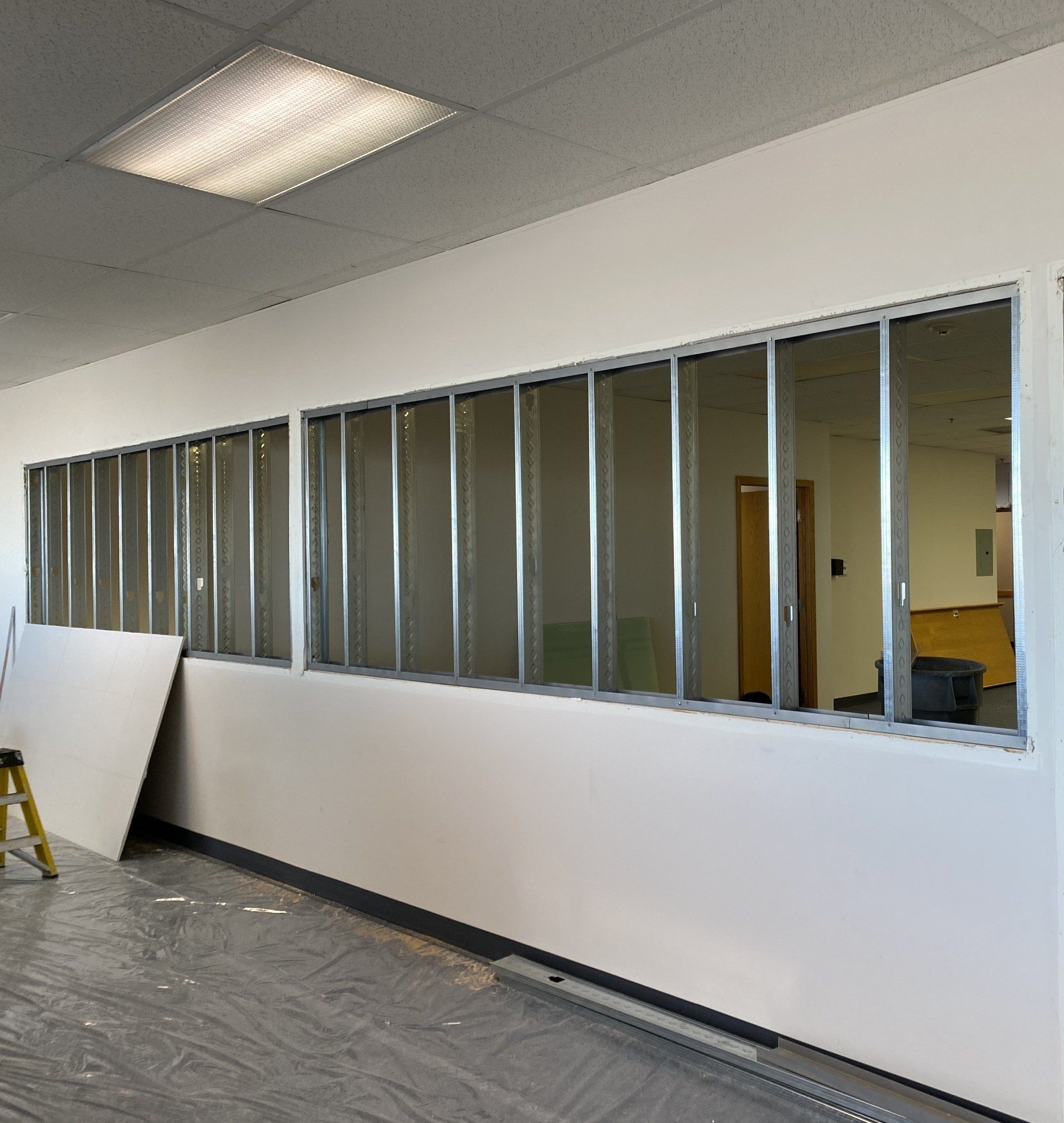 A room with a lot of windows and a ladder on the floor.