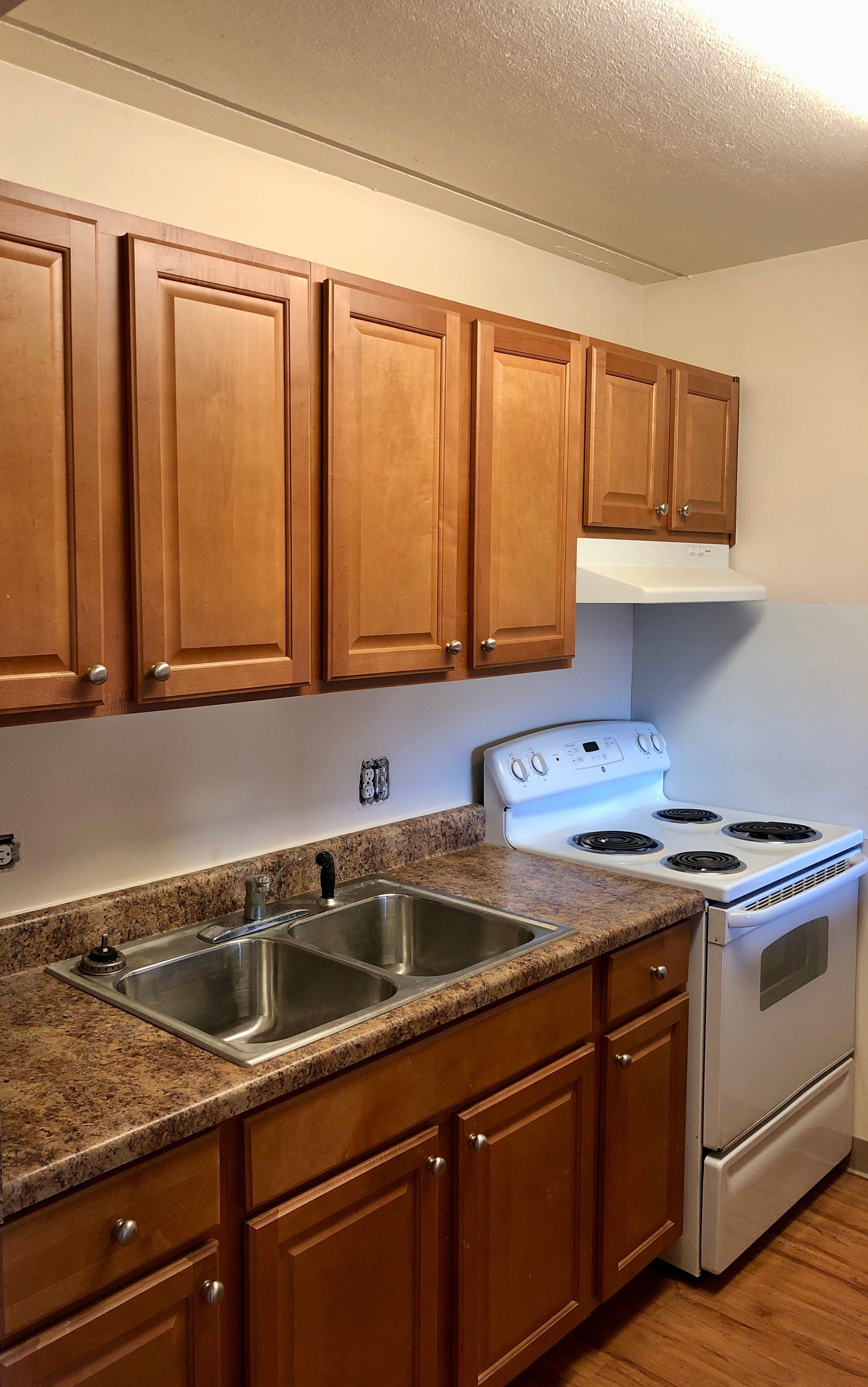 A kitchen with wooden cabinets , a stove and a sink.