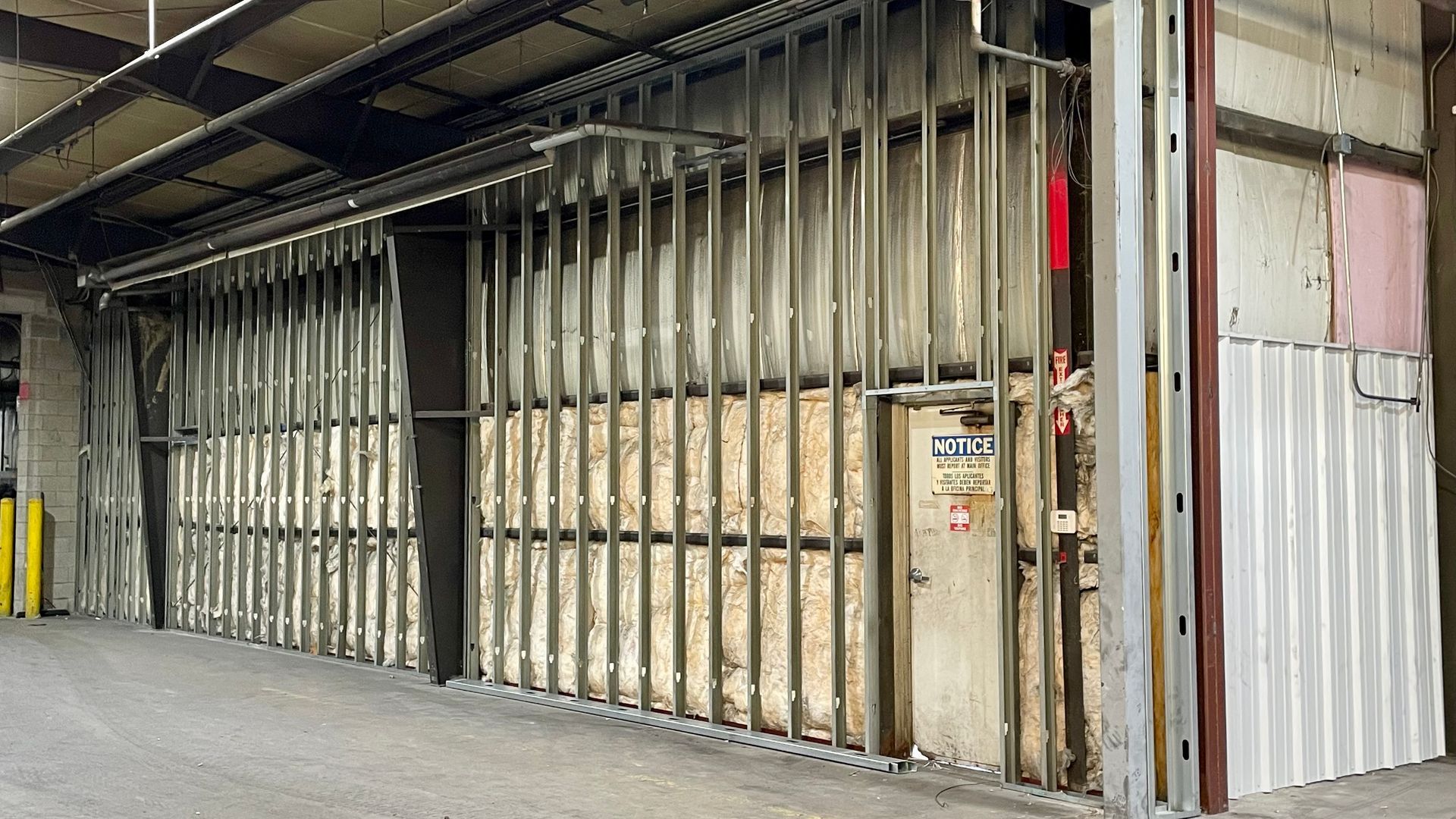 A building under construction with a metal wall and a door.