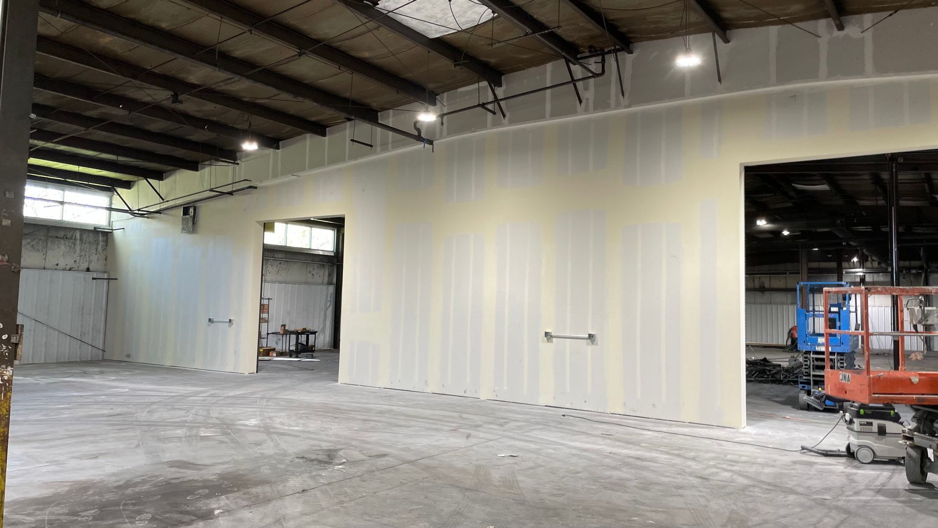 A large empty warehouse with white walls and a lift.