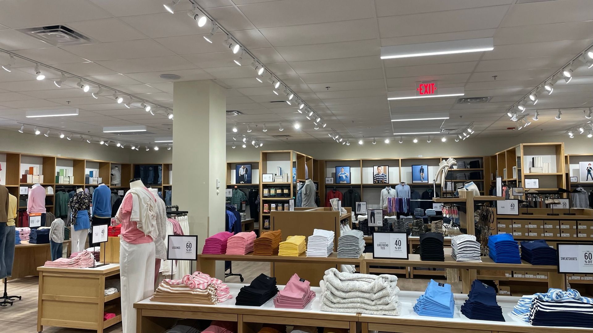 A store filled with lots of clothes and a red exit sign.