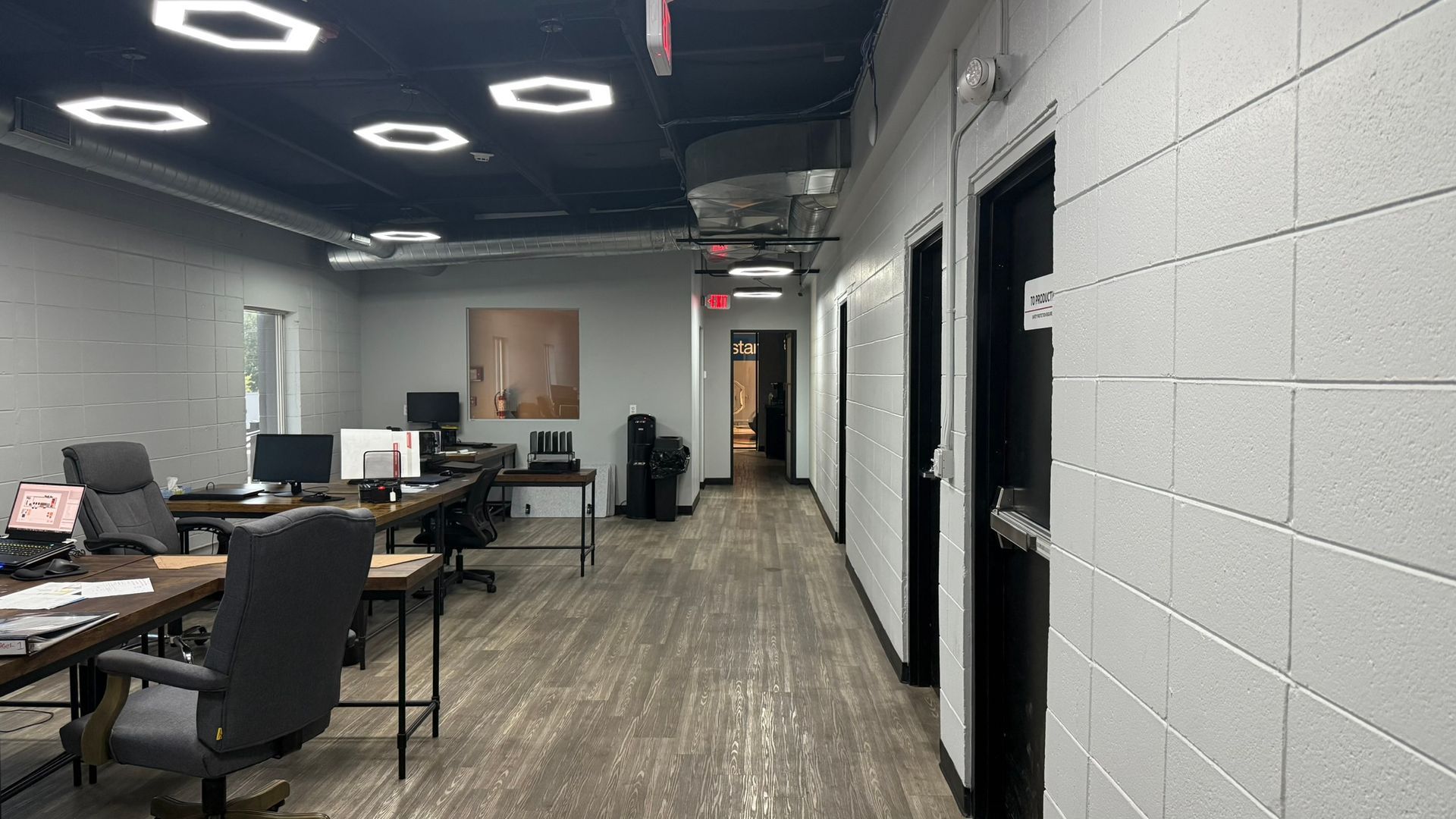 A long hallway in an office with a desk and chairs.