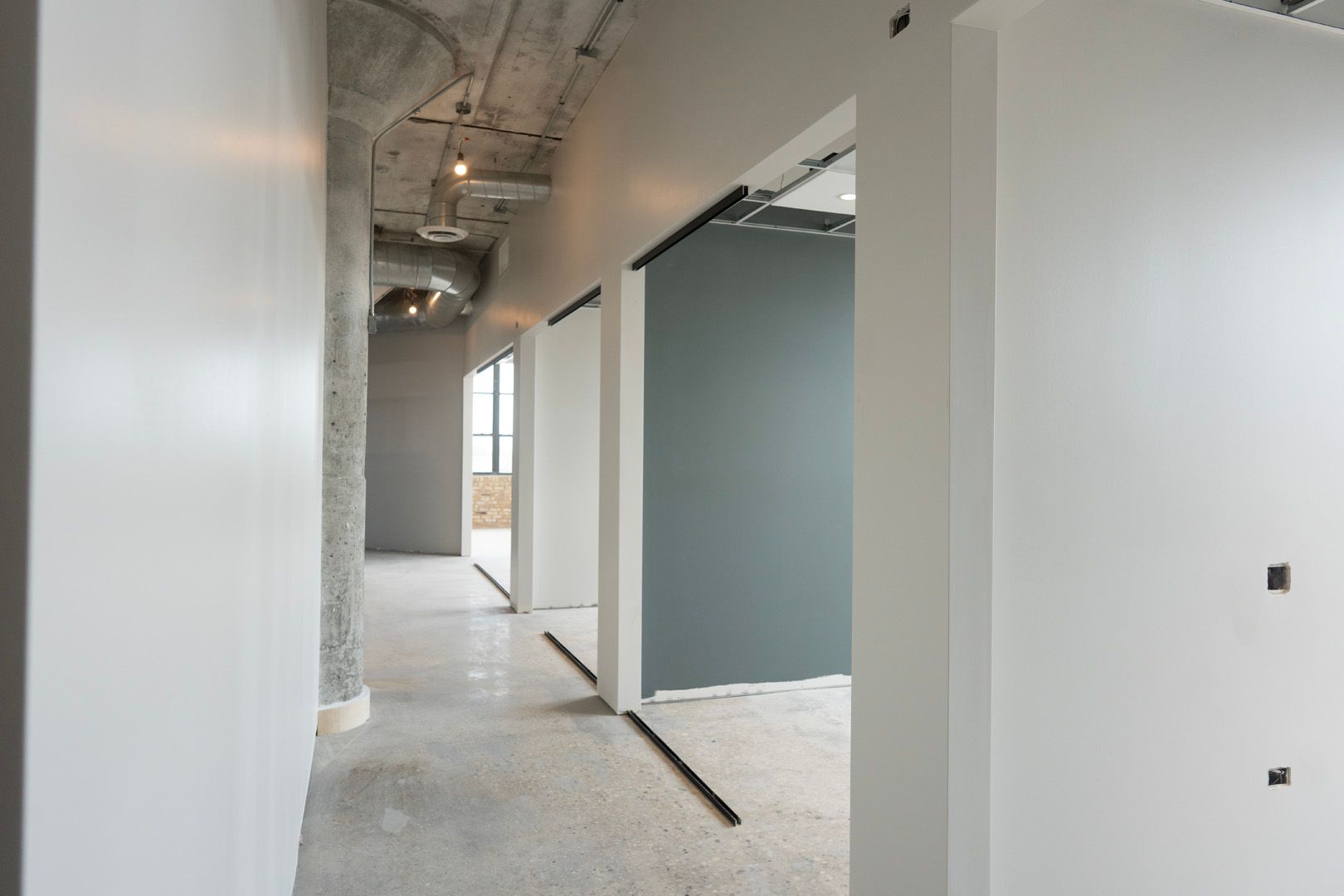 A hallway with white walls and gray walls in a building under construction.