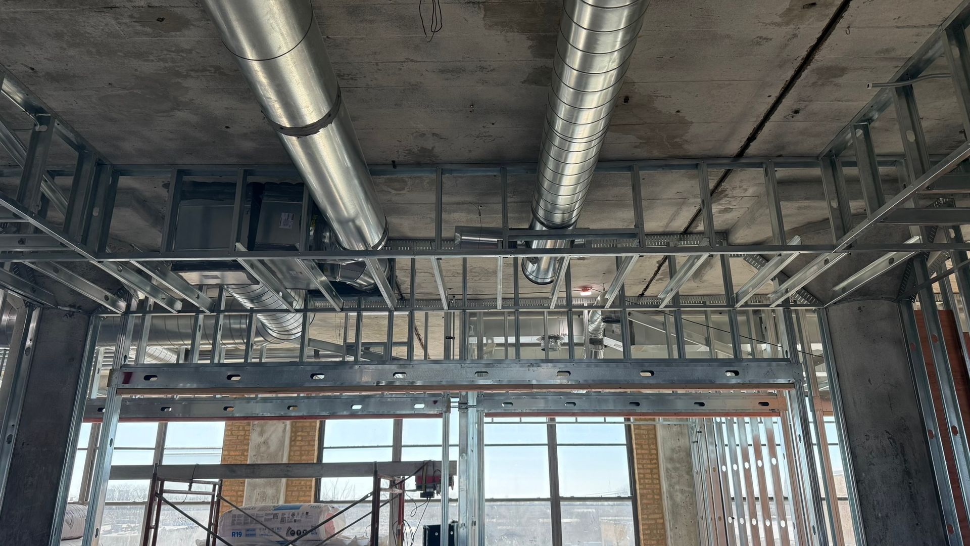 A building under construction with a lot of pipes coming out of the ceiling.