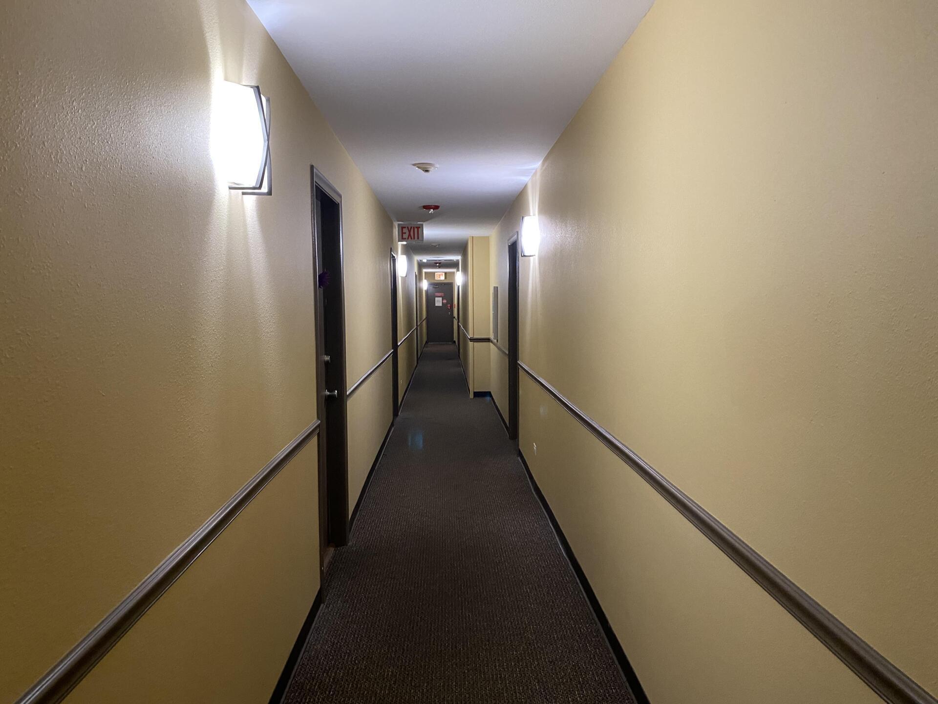 A long hallway with yellow walls and brown carpet