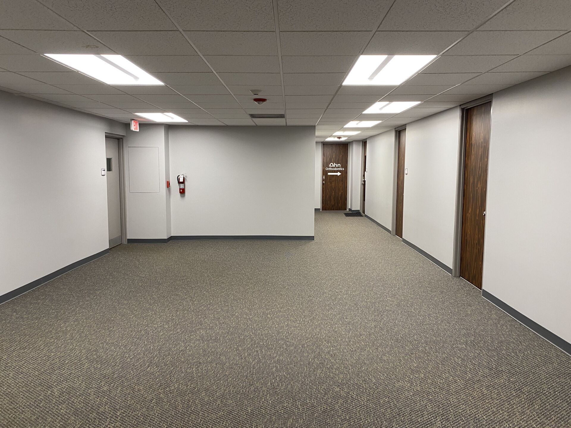 An empty hallway with a fire extinguisher on the wall.