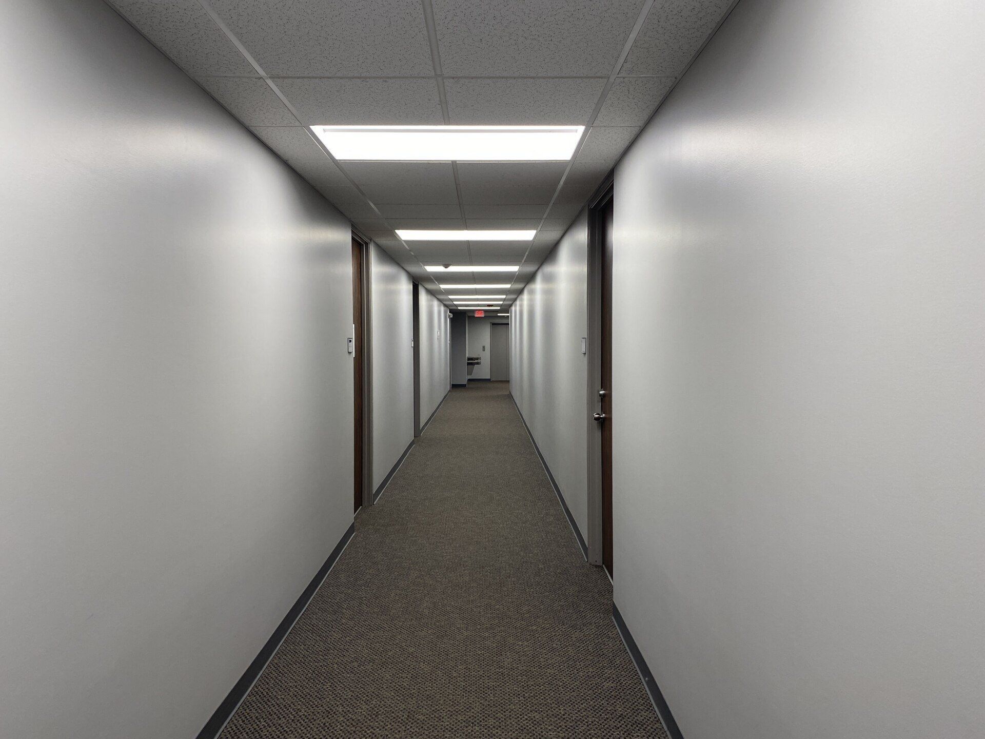 A long hallway with white walls and brown carpet