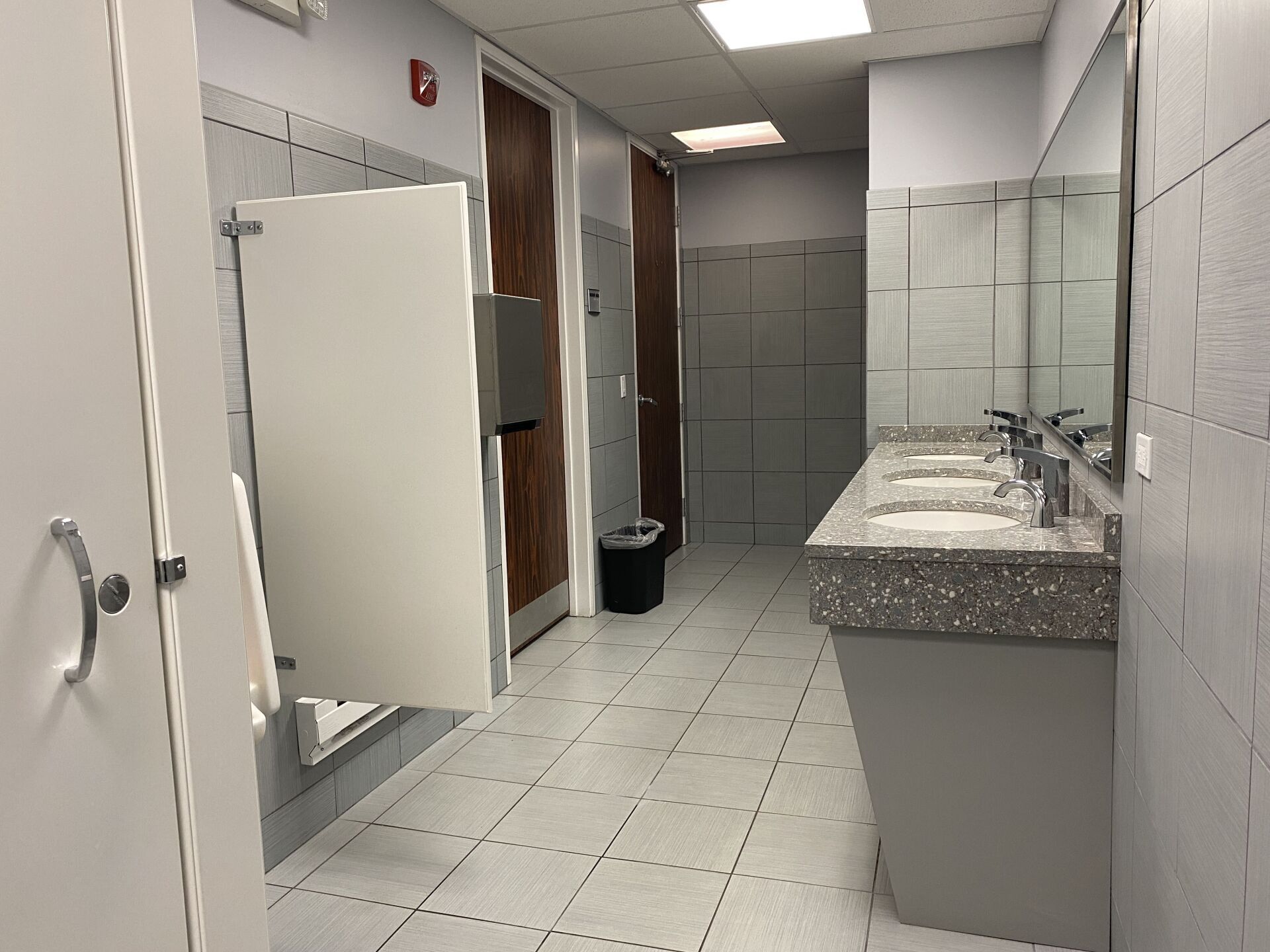 A bathroom with two sinks , a mirror and lockers.