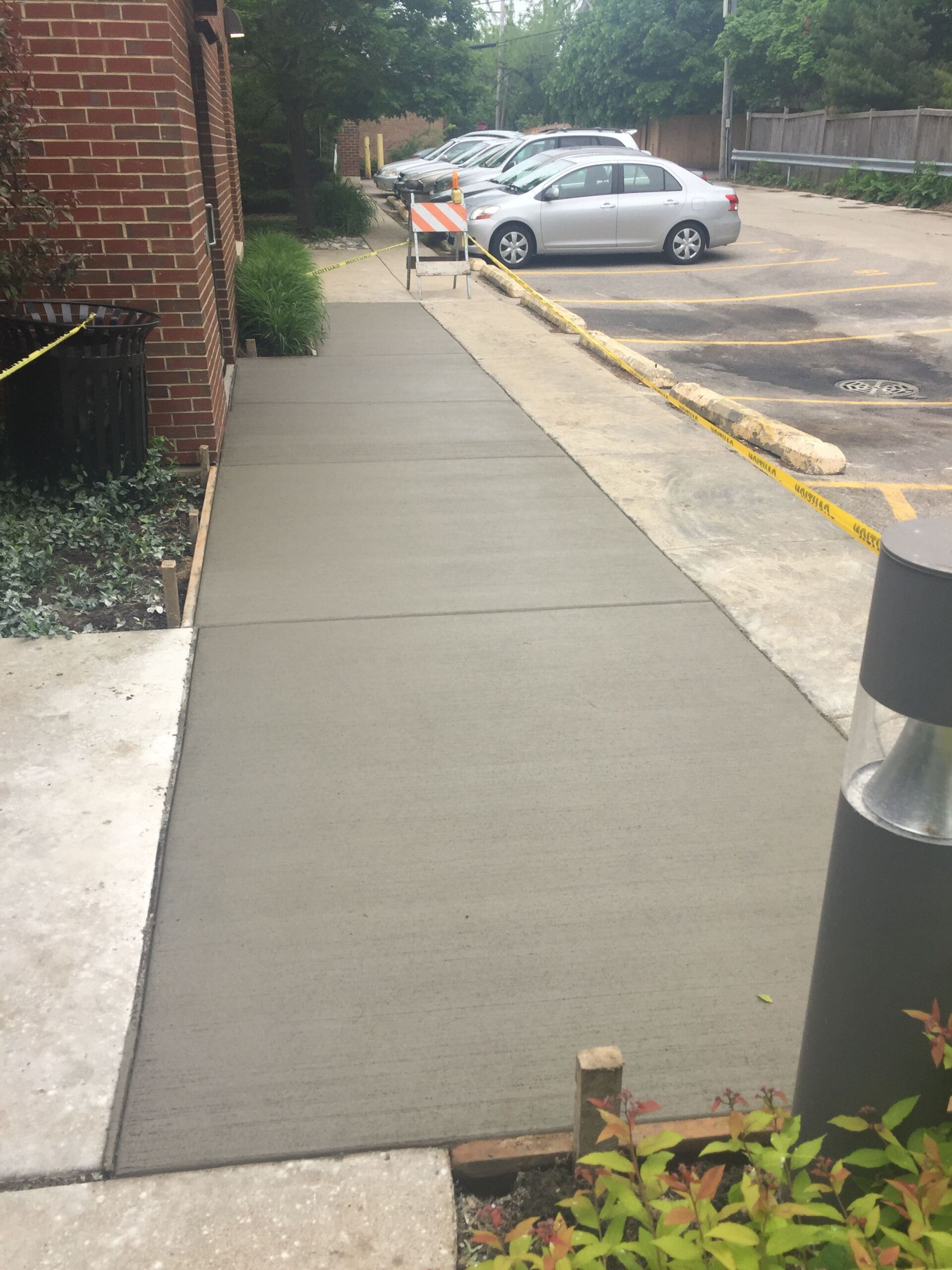 A sidewalk is being built in front of a parking lot.