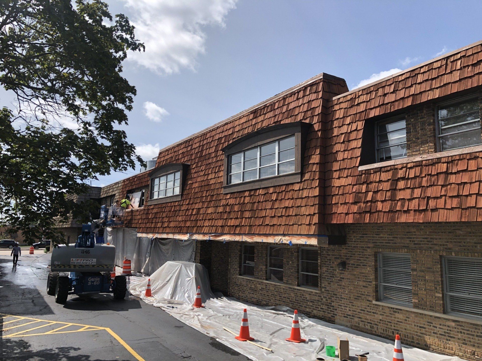 A large brick building with a lot of windows is being painted.