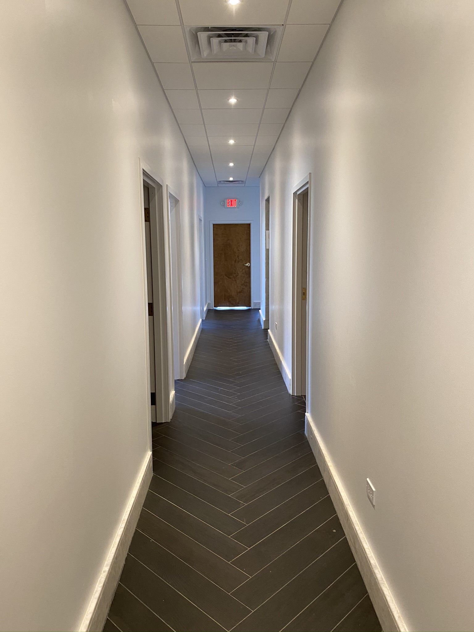 A long hallway with white walls and a black floor