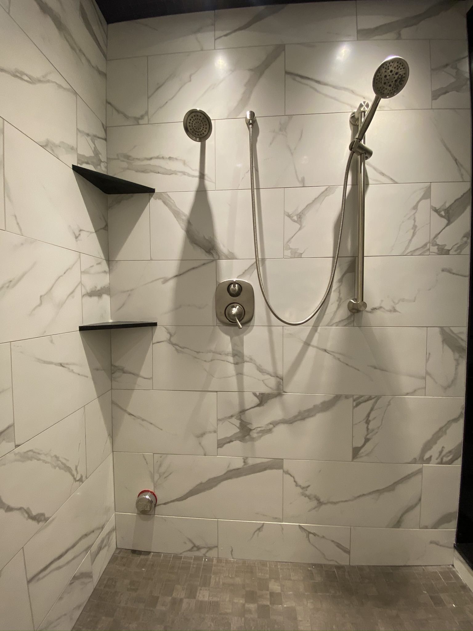 A bathroom with marble tiles and a walk in shower with two shower heads.