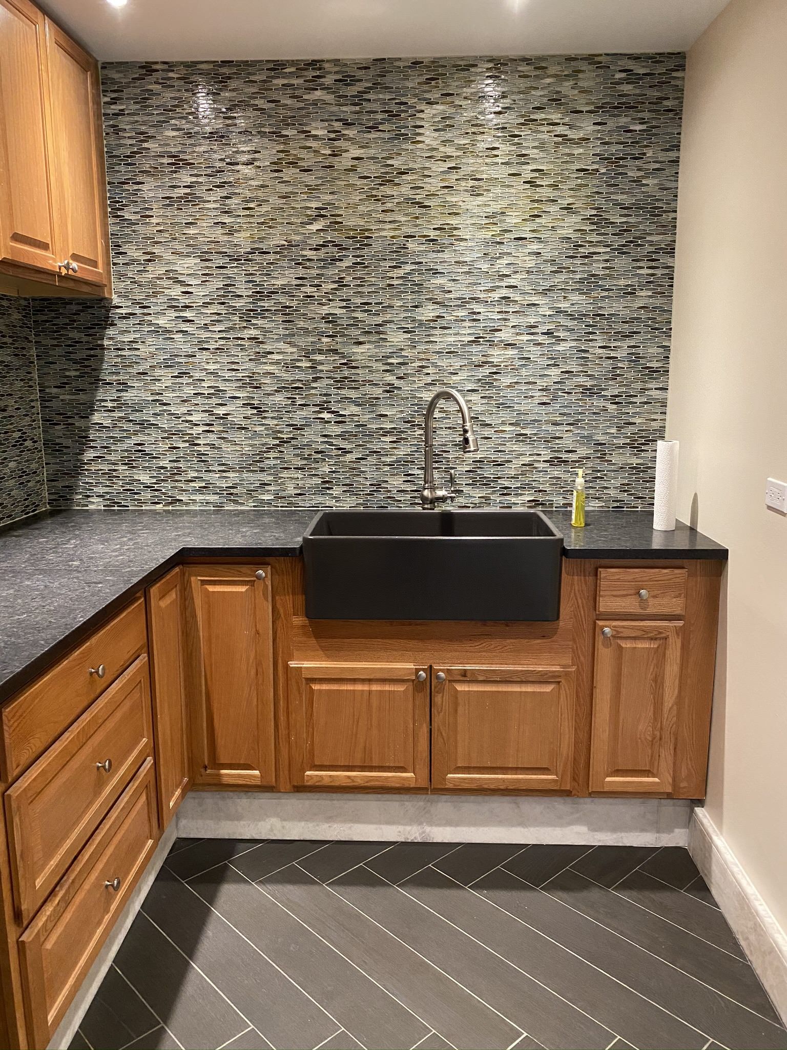 A kitchen with wooden cabinets and a black sink.