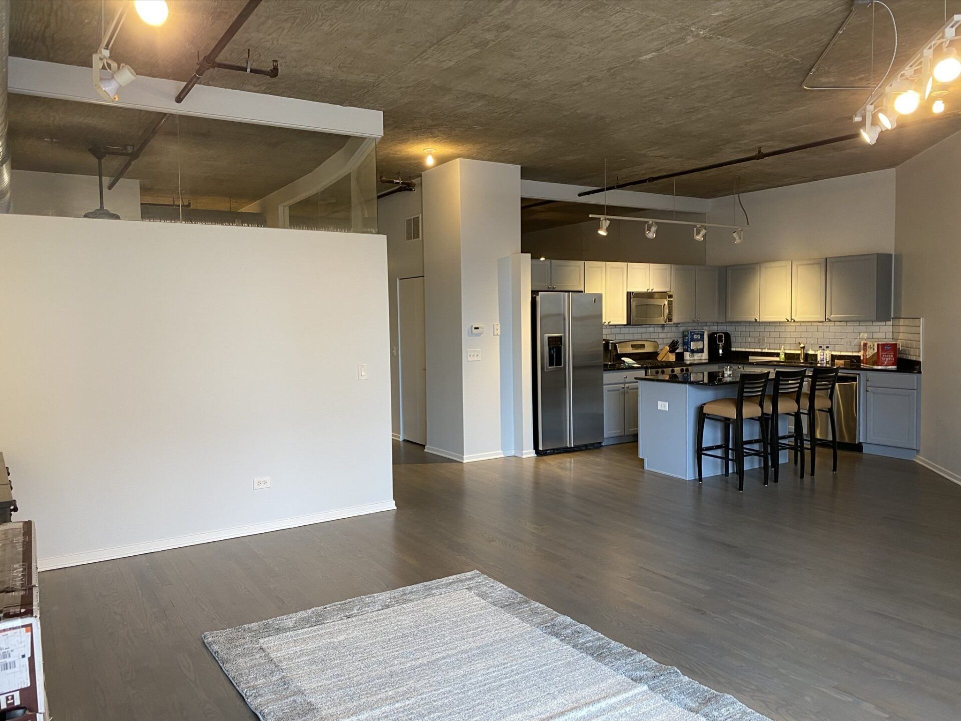 A living room with a rug and a kitchen in the background