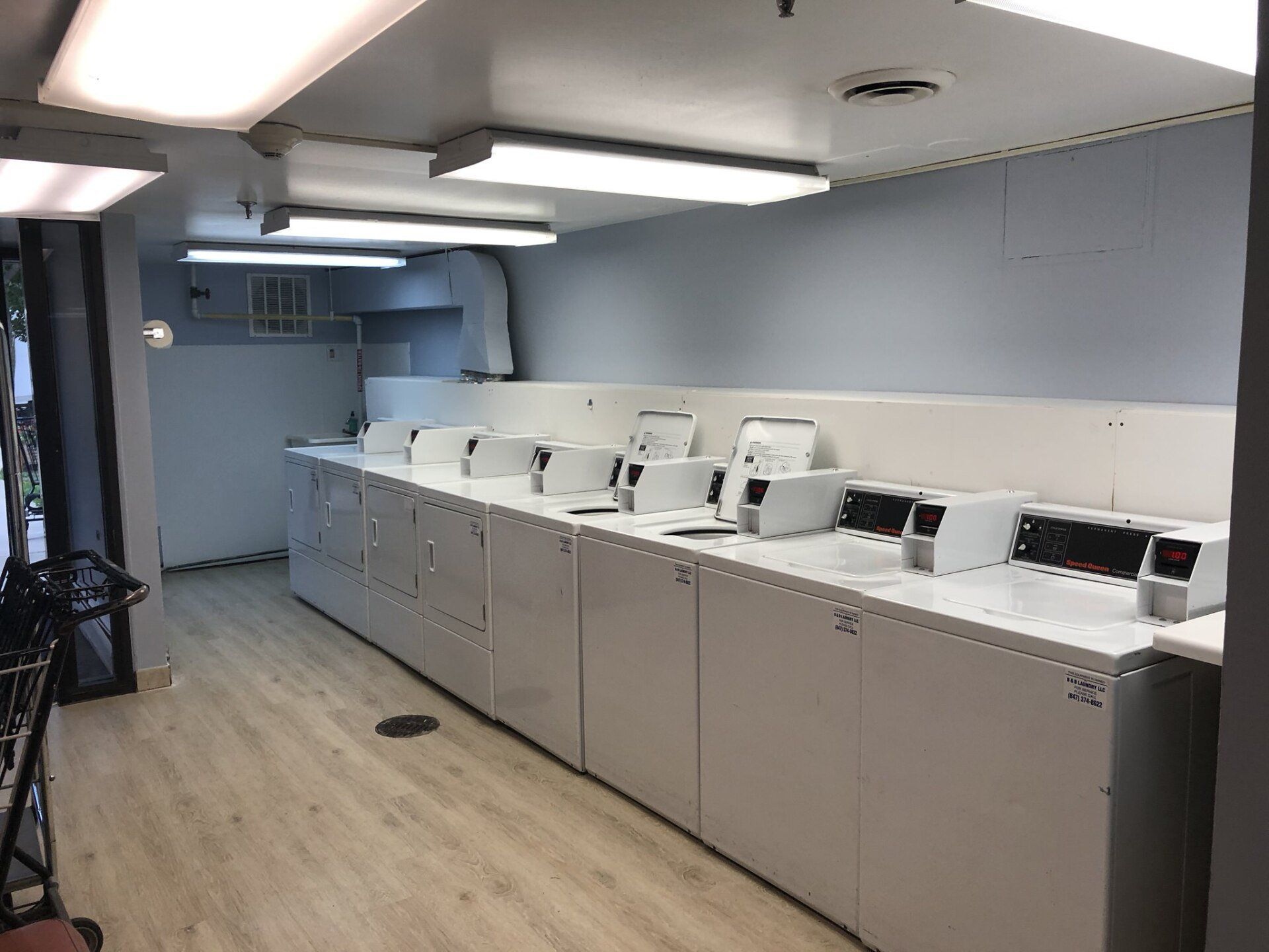 A laundromat with a lot of white washers and dryers.