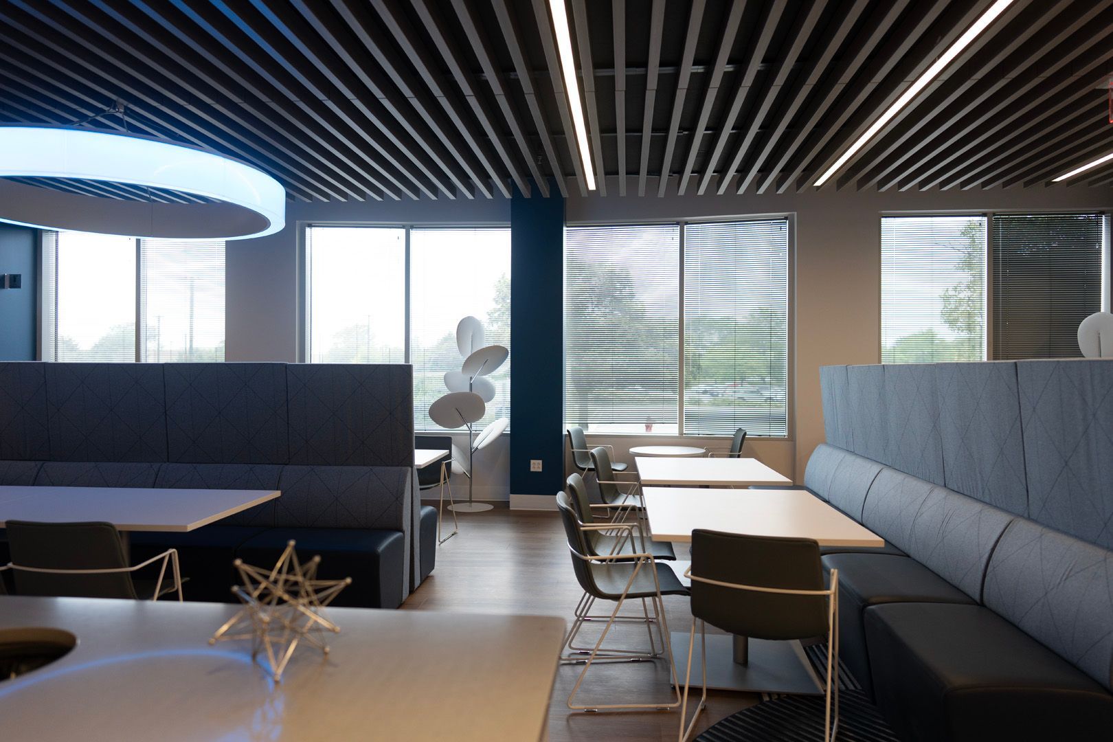 A dining room with tables and chairs and a circular light hanging from the ceiling.