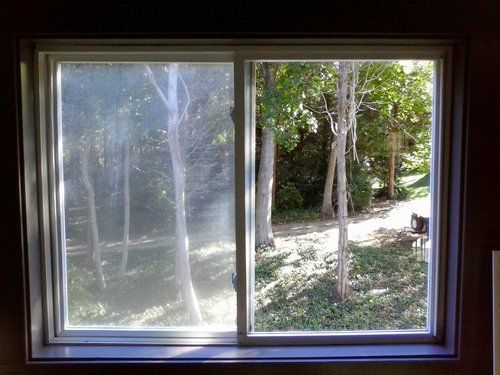 A sliding glass window with a view of a forest.