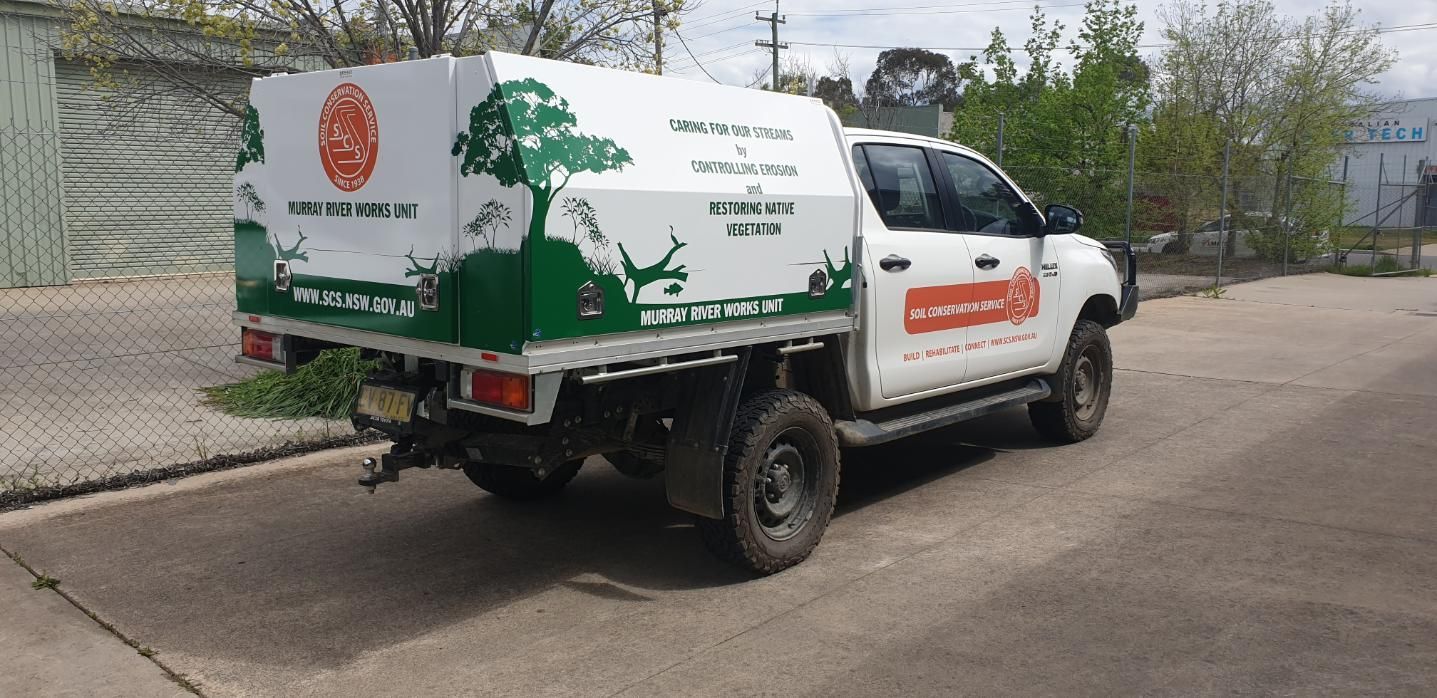A White Truck With a Green Canopy is Parked on the Side of the Road — Robinsons Sign Makers in Lavington, NSW