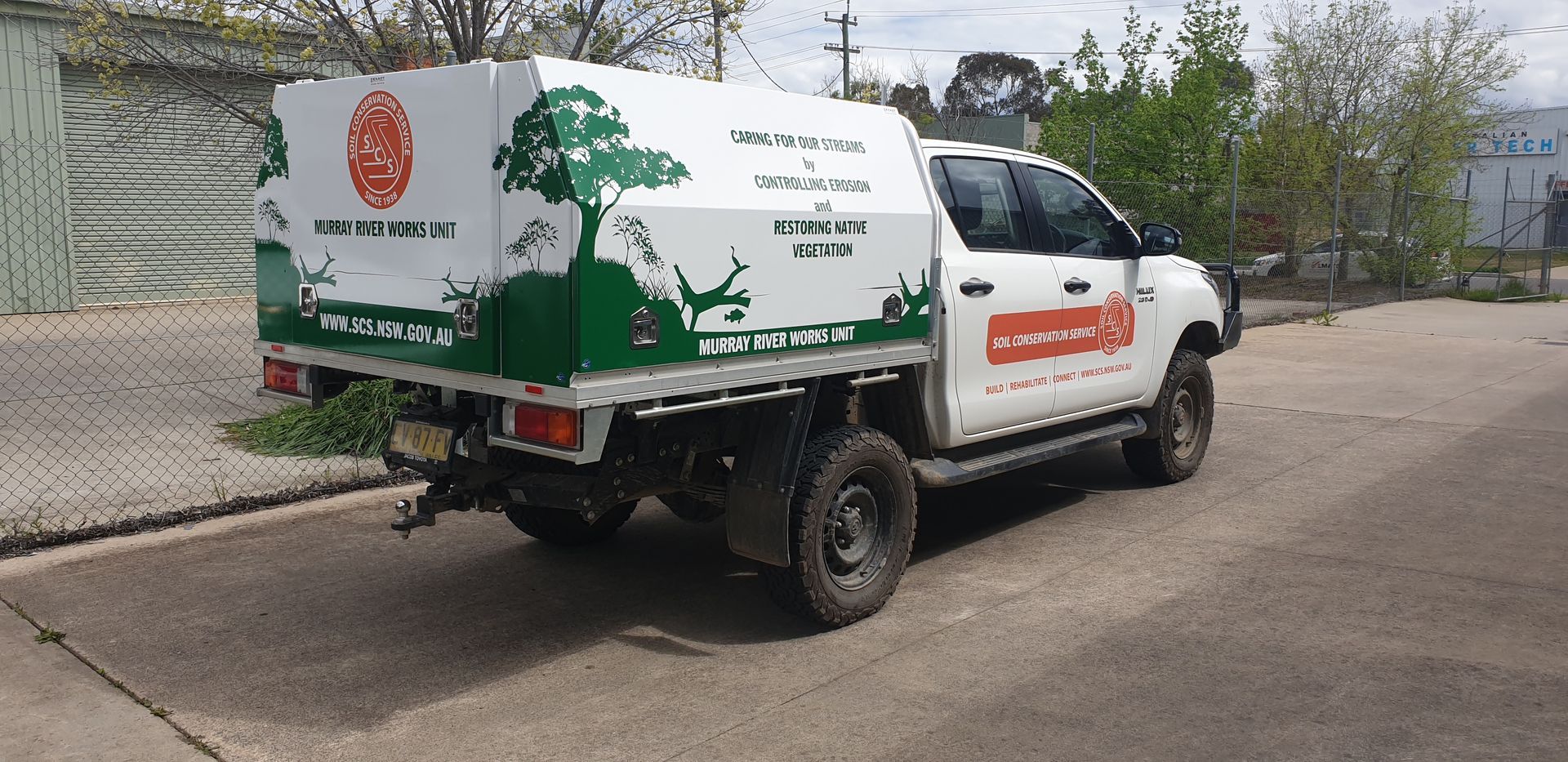 A White Truck With a Green Canopy is Parked on the Side of the Road — Robinsons Sign Makers in Lavington, NSW