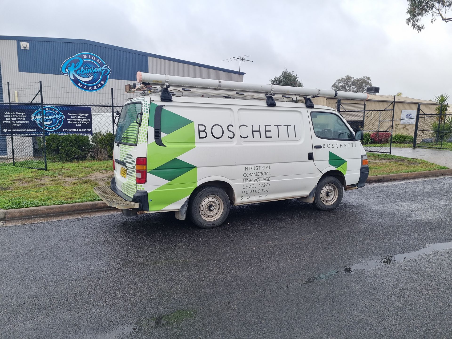 A White Van is Parked on the Side of the Road in Front of a Building — Robinsons Sign Makers in Lavington, NSW