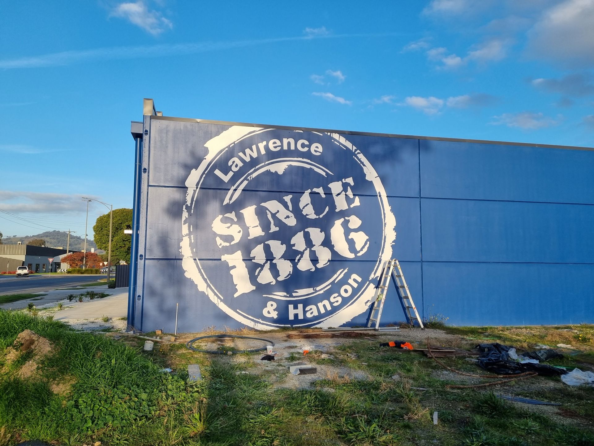 A Blue Building With a Sign on It That Says Lawrence Since 1886 and Hanson — Robinsons Sign Makers in Lavington, NSW