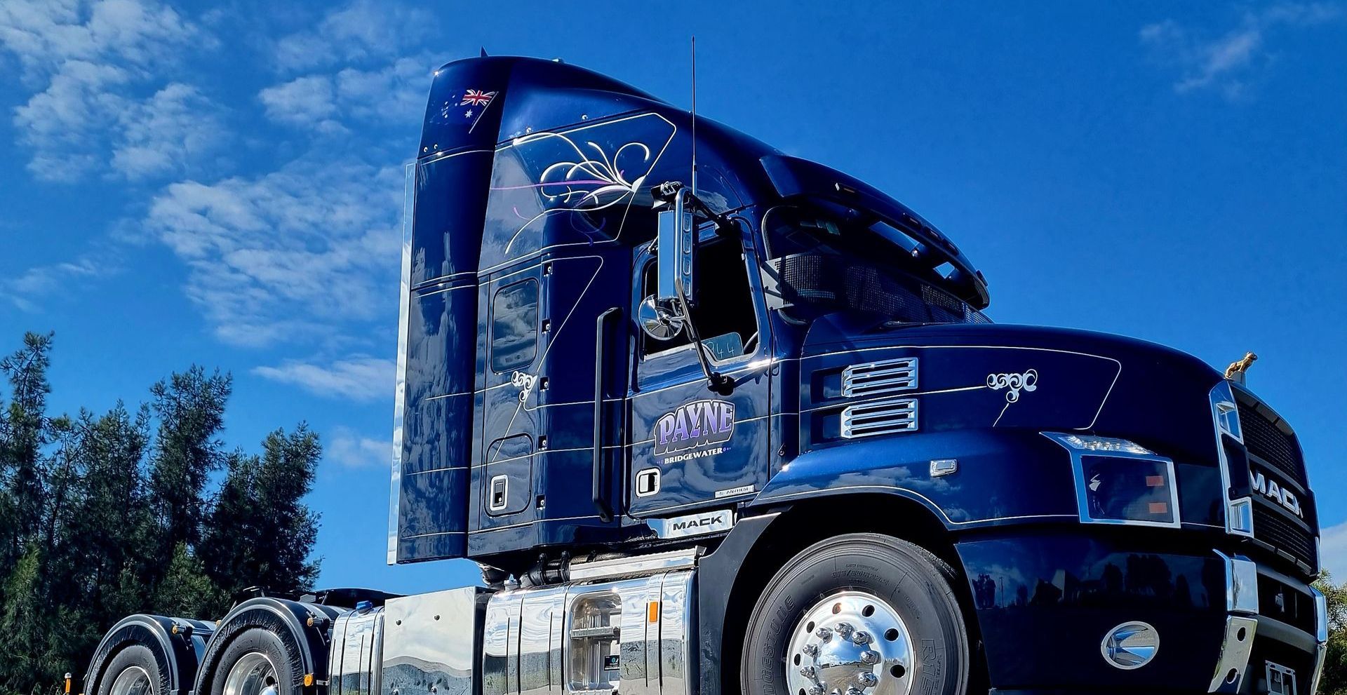 A Navy Blue and White Semi Truck is Parked in Front of a Building — Robinsons Sign Makers in Canberra, ACT
