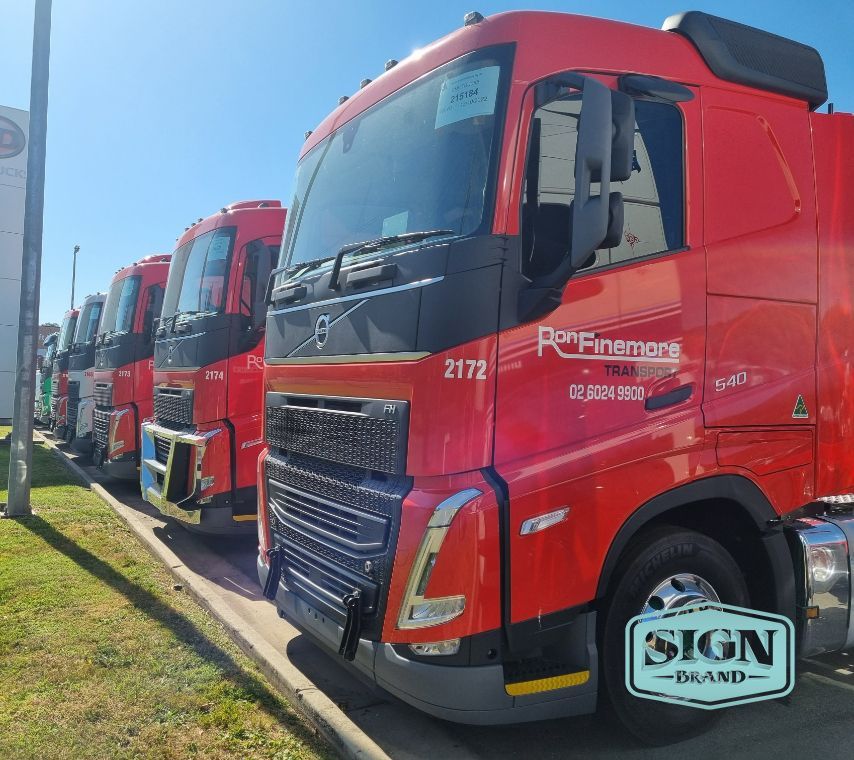 A Row of Red Trucks Are Parked in Front of a Sign That Says Sign Brand — Robinsons Sign Makers in Lavington, NSW