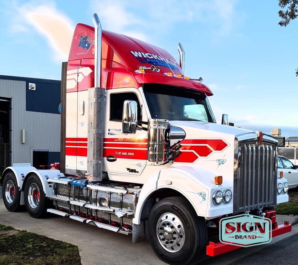 A Red and White Semi Truck is Parked in Front of a Sign Brand Building — Robinsons Sign Makers in Lavington, NSW