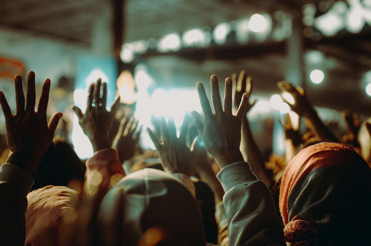 A crowd of people are raising their hands in the air at a concert.