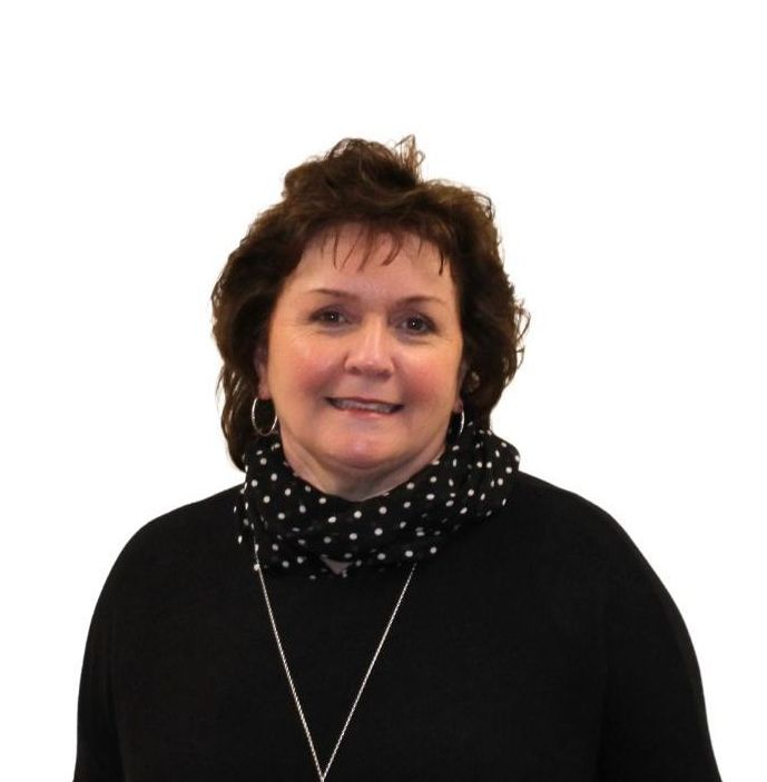 A woman wearing a black sweater and polka dot scarf smiles for the camera