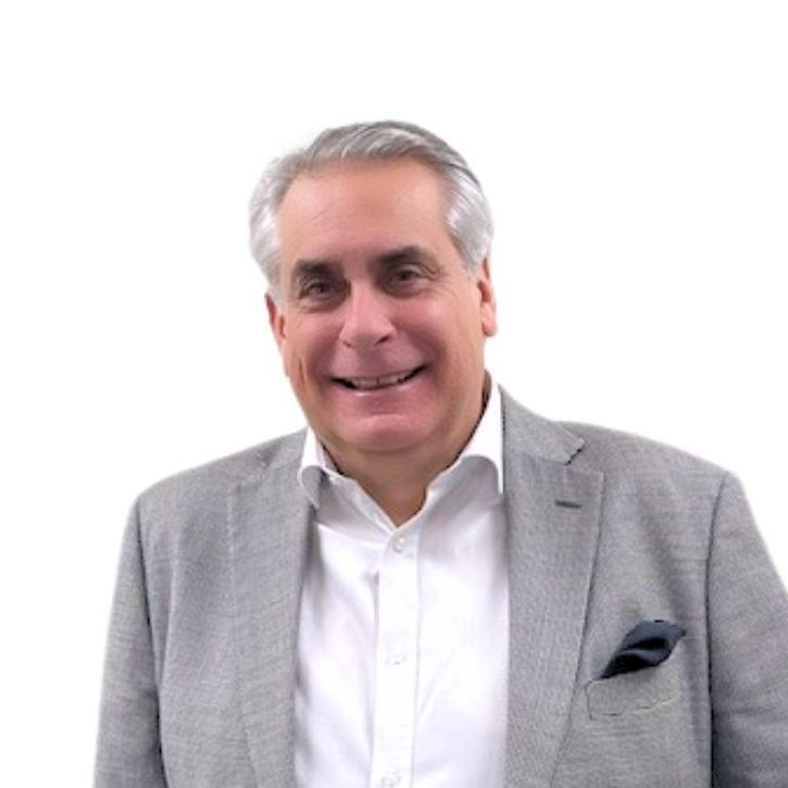 A man wearing a grey jacket and white shirt smiles for the camera