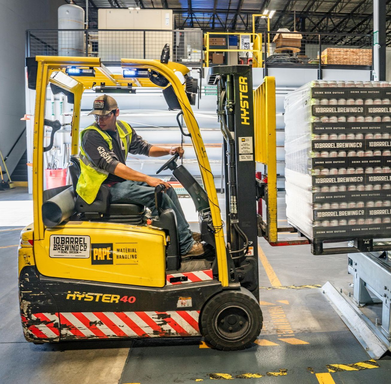 A man is driving a hyster forklift in a warehouse