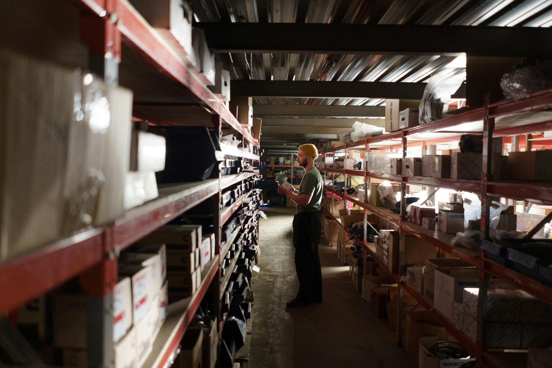 A man is standing in a warehouse looking at a tablet.