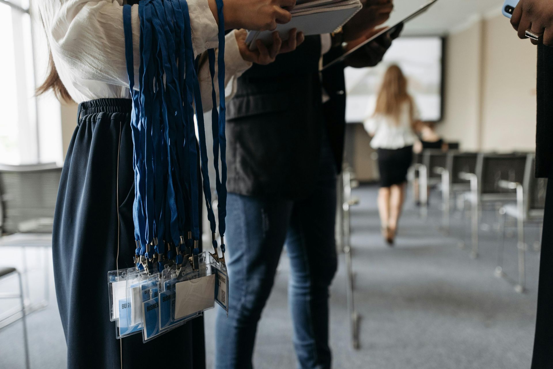 A woman is holding a bunch of lanyards in a conference room.