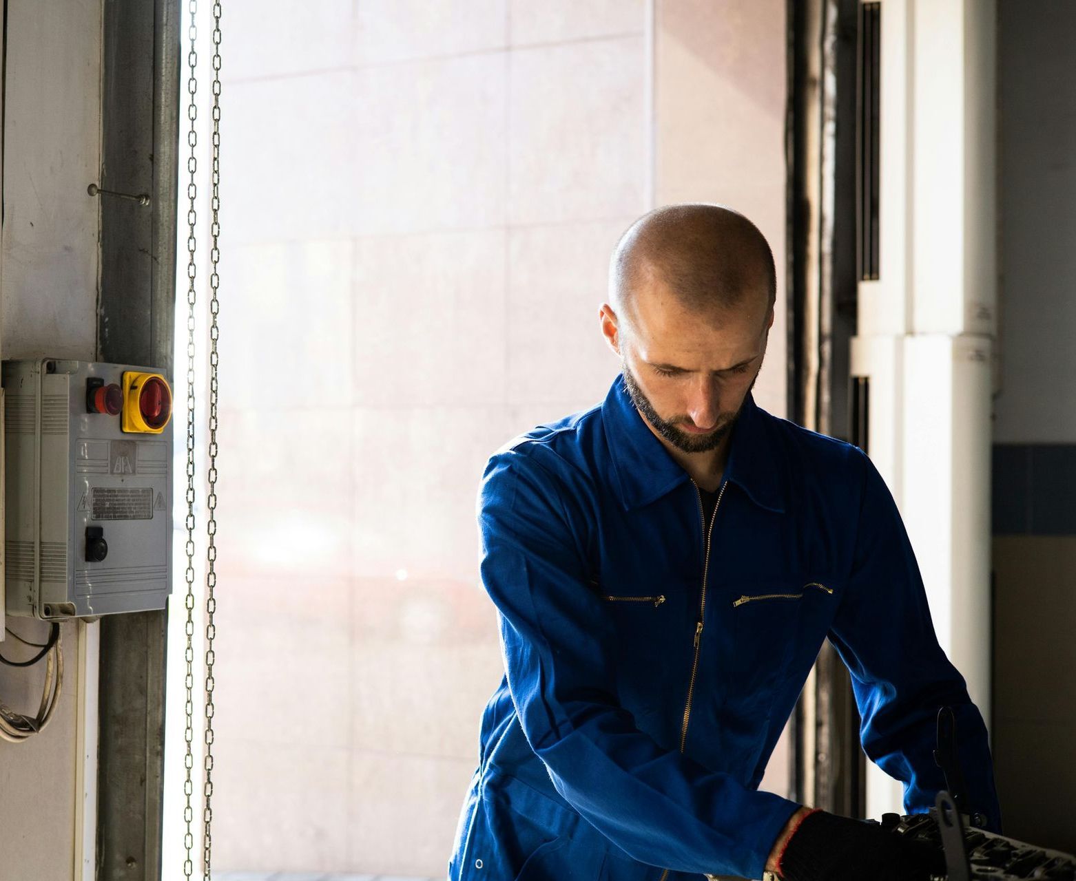 A man in a blue jacket is working on a machine.