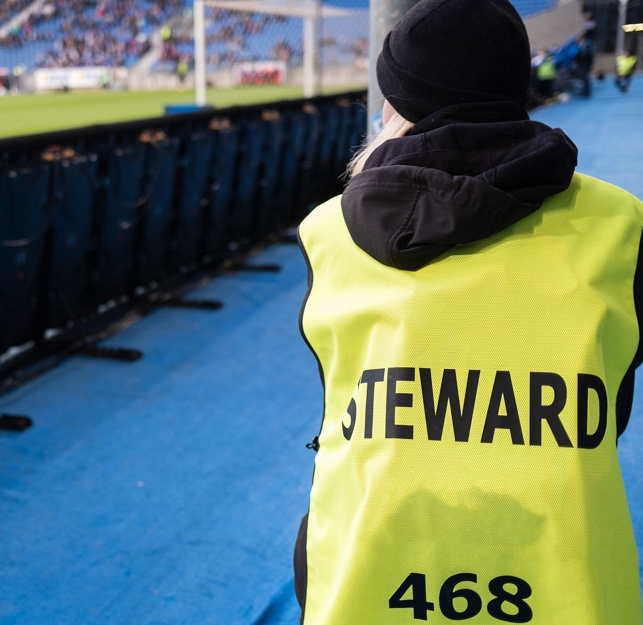 A person wearing a yellow vest with the word steward on it