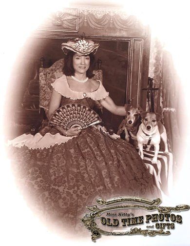 A woman in a dress is holding a fan and a dog.