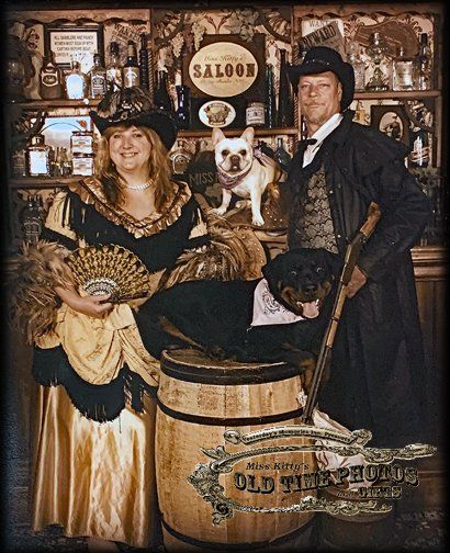 a man and woman are posing for a picture in front of a saloon sign
