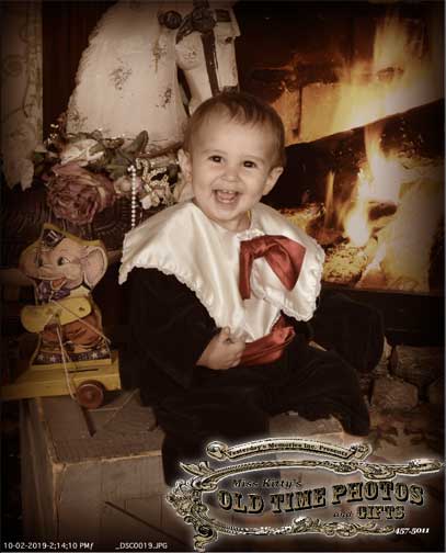 an old time photo of a baby in front of a fireplace- Miss Kitty's Old Time Photos and Gifts    Corolla Outer Banks NC