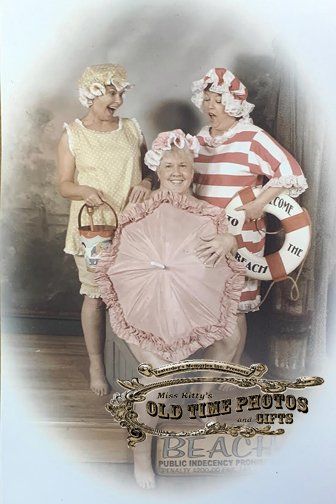 three women are posing for a picture while wearing striped bathing suits .