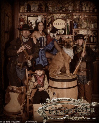 a family posing for a picture in a saloon with a dog on a barrel .