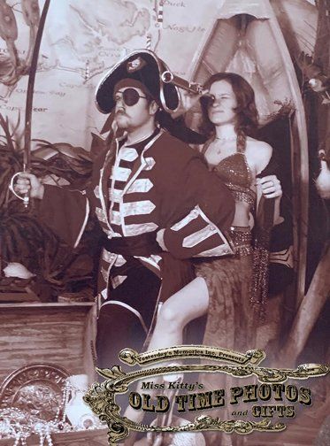 a sepia photo of a man dressed as a pirate and a woman dressed as a belly dancer