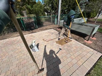 A man is leveling some pavers on a patio with paver restoration tools.
