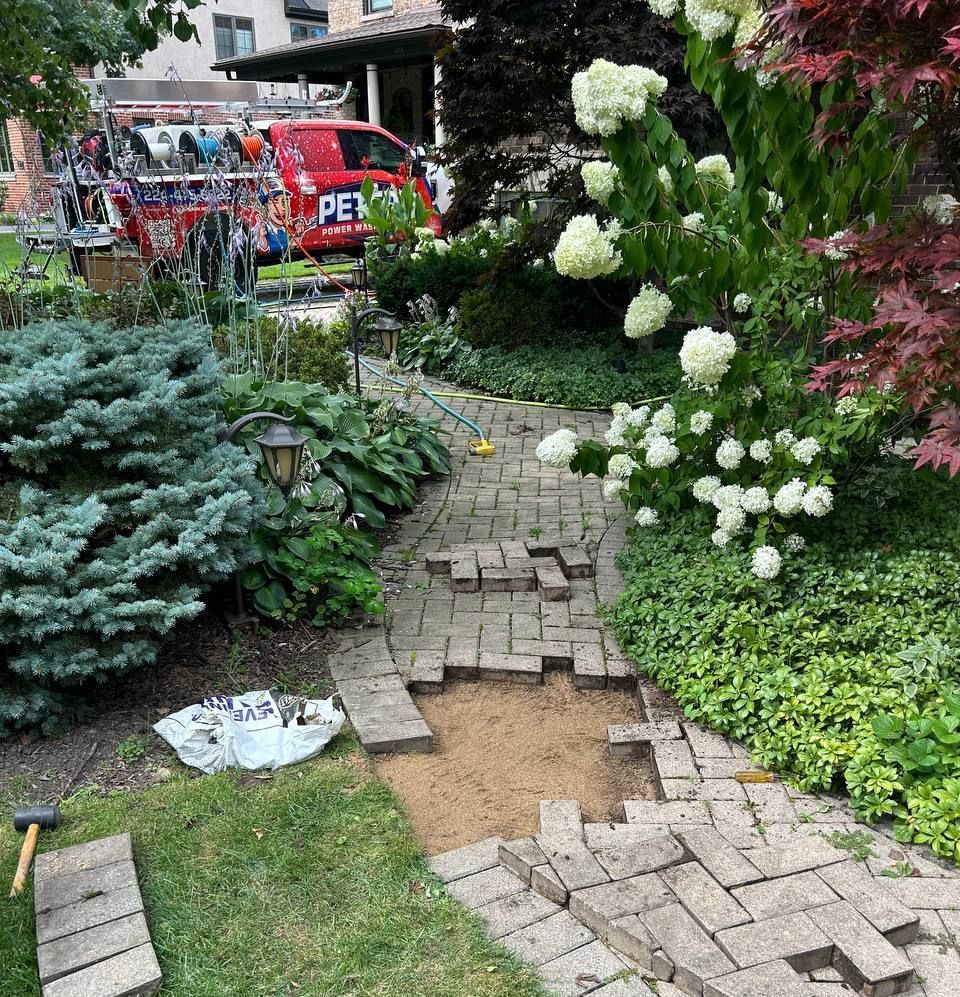 The team of Peter's Pavers Restoration working on a paver pathway and level out some uneven pavers. 